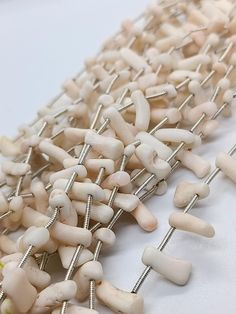 several white beads and metal pins on a table