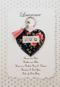 a heart shaped keychain with the word hug on it and a tasselled flower