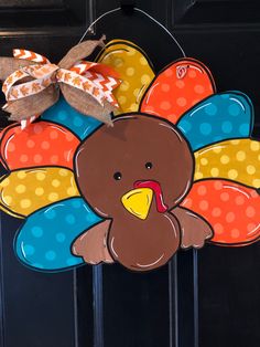 a colorful turkey door hanger with a bow on it