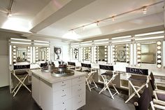 a room filled with lots of white chairs and vanity mirrors on the wall next to each other