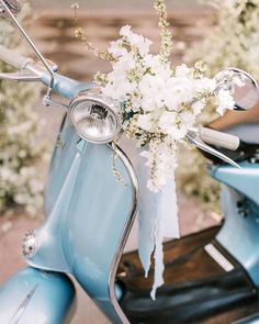 a blue scooter with white flowers on the seat and handlebars is parked