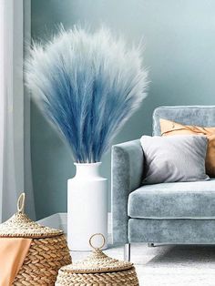 a living room filled with furniture and a blue plant in a white vase on top of a table