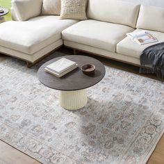 a living room with a couch, coffee table and rug on the floor in front of it