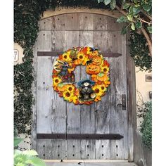 a wooden door with a wreath decorated with sunflowers and pumpkins on it