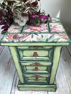 a green painted dresser with flowers on it and a skull in the middle next to it