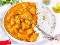 a white bowl filled with rice and curry next to a red pepper shaker on the side