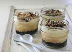 four desserts in small glass jars with spoons