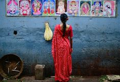 a woman in a red sari standing next to a wall with paintings on it