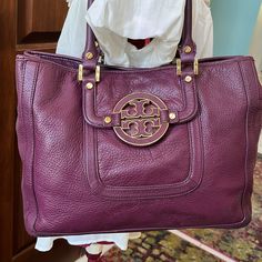 Tory Burch Pretty Purple Shoulder Bag Satchel Handbag Purse Genuine Pebbled Leather In Purple Gold Tone Hardware Large Round Gold Tone Rimmed Purple Leather Tory Logo Front And Center Has Slip Pocket Under Logo Back Exterior Studded Slip Pocket 2 Rolled Satchel Handles Square Gold Handle Mounts Sides Have Top Snaps To Tighten Ends Or Open For More Room Bottom Has 4 Gold Tone Rivets For Feet Magnetic Snap Top Closure Interior Lined In Light Tan Fabric/ Tory Round Logos Inside Contains 1 Large Zip Designer Purple Travel Bag, Luxury Purple Shoulder Bag With Top Carry Handle, Luxury Purple Shoulder Bag With Top Handle, Designer Purple Shoulder Bag With Detachable Handle, Purple Leather Shoulder Bag With Detachable Handle, Designer Purple Top Handle Shoulder Bag, Designer Purple Bag With Gold-tone Hardware, Designer Purple Double Handle Shoulder Bag, Luxury Purple Shoulder Bag With Removable Pouch