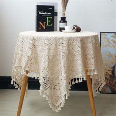 the table is covered with white crocheted doily and has a vase on it