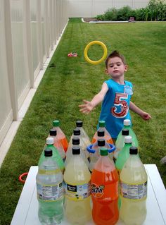 a young boy standing in front of a table full of bottles of water and drinks