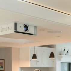 a camera mounted to the ceiling above a kitchen counter top with lights hanging from it