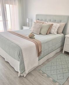 a bedroom with a bed, dresser and rugs on the wooden floor in front of windows