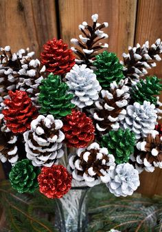 a glass vase filled with pine cones covered in tinsel and colored snowflakes