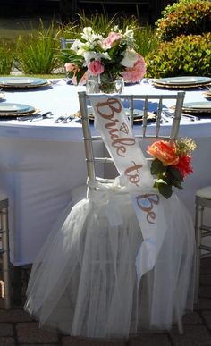 a chair with a sash around it that says bride to be on the side and flowers in vases at the back