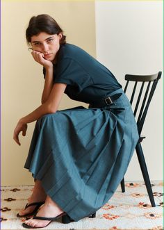 a woman sitting on a chair with her hand under her chin