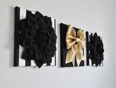 three black and gold bows are hanging on the wall next to two white striped paintings