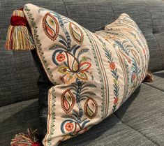 a decorative pillow with tassels is on a gray couch in the living room