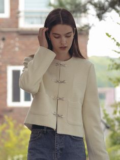 a woman in a white jacket is holding her head with one hand and looking down