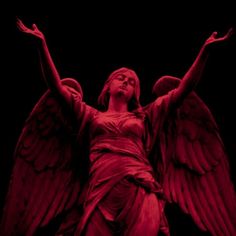 an angel statue with red lighting on it's face and hands in the air