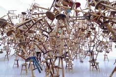 many wooden chairs and stools are stacked together