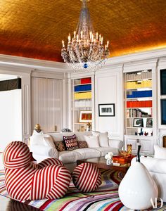 a living room filled with lots of furniture and a chandelier hanging from the ceiling