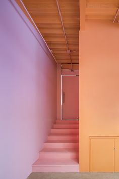 an empty room with pink walls and stairs