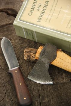 a knife and some wood on a table next to a box with an open book