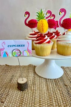 cupcakes with pineapples and flamingos are on a cake plate