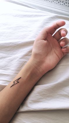 a person's arm with a small arrow tattoo on the left side of their arm