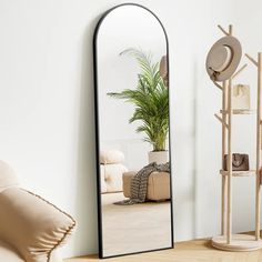 a large mirror sitting on top of a wooden floor next to a chair and potted plant