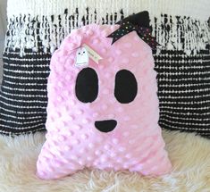 a pink stuffed animal pillow sitting on top of a white fur covered floor next to two black and white pillows