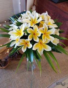 a vase filled with yellow and white flowers on top of a table next to a candle