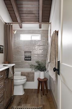 a white toilet sitting in a bathroom next to a sink and wooden floored walls