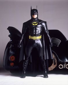 the batman action figure is posed next to his batmobile