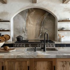 a kitchen with marble counter tops and wooden cabinets in front of an arched doorway that leads to the outside