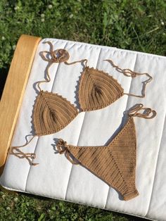 two crocheted bikinisuits sitting on top of a white blanket in the grass