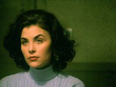 a woman with dark hair wearing a turtle neck sweater and looking off to the side