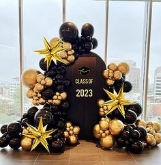 a graduation balloon arch with gold stars and balloons in the shape of a mailbox