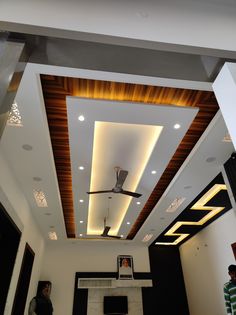 a man standing in a living room with a ceiling fan and lights on the ceiling