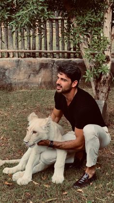 a man kneeling down next to a white dog