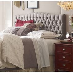 a bed with white headboard and pillows on top of it next to a dresser