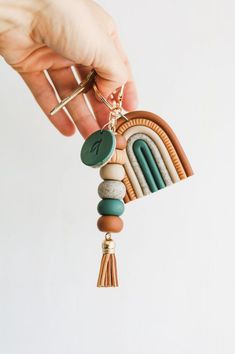 a hand holding a keychain made out of wood and beads with a rainbow charm hanging from it