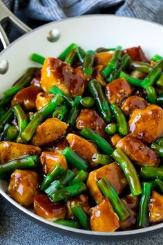 a pan filled with green beans and tofu in sauce on top of a table