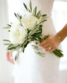 a bride holding a bouquet of white flowers