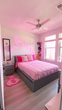 a bedroom with a pink bed and white walls, hardwood flooring and ceiling fan