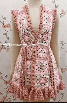 a pink crocheted dress is displayed on a mannequin