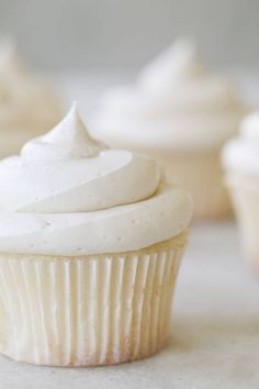 cupcakes with white frosting sitting on a table