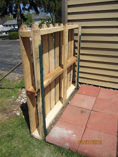 a wooden gate sitting on top of a grass covered field next to a brick walkway