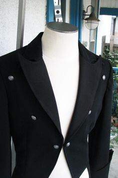 A classic dress coat with gothic detailing. This piece has peak lapels and a curved upper collar so that the points overlap. The fronts of the tailcoat just kiss and finish with a hook and eye. The unique pointed cuffs feature 6 buttons. And the back tightens with a belt. The piece is made from a gorgeous 12oz wool suiting. ----------------------------------- We can make a tailcoat in any style. From steampunk, to Regency, to stunning white tie. Contact us with the details that you would like be Steampunk Long Sleeve Formal Outerwear, Gothic Formal Outerwear For Fall, Formal Gothic Outerwear For Fall, Gothic Formal Winter Outerwear, Gothic Black Outerwear For Formal Occasions, Black Gothic Outerwear For Formal Occasions, Victorian Black Formal Outerwear, Fitted Double-breasted Outerwear For Costume, Fitted Gothic Outerwear With Button Closure